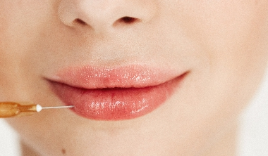 Close up photo of medical botox injection in lips over white background. Facial treatment.